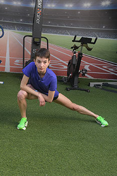 Η αθλήτρια βρίσκεται σε ύπτια θέση σε γαλάζιο στρώμα άσκησης με τα πόδια ασφαλισμένα στη συσκευή και εκτελεί ισομετρική άσκηση οπίσθιων μηριαίων.