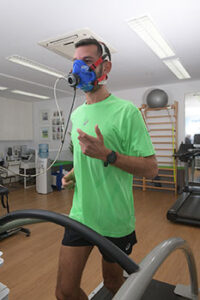 Επαγγελματίας εργοφυσιολόγος παρακολουθεί αθλητή κατά τη διάρκεια εξέτασης VO₂ max πάνω σε διάδρομο τρεξίματος.