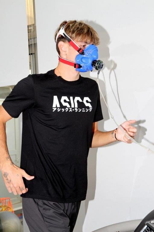 Επαγγελματίας εργοφυσιολόγος παρακολουθεί αθλητή κατά τη διάρκεια εξέτασης VO₂ max πάνω σε διάδρομο τρεξίματος.